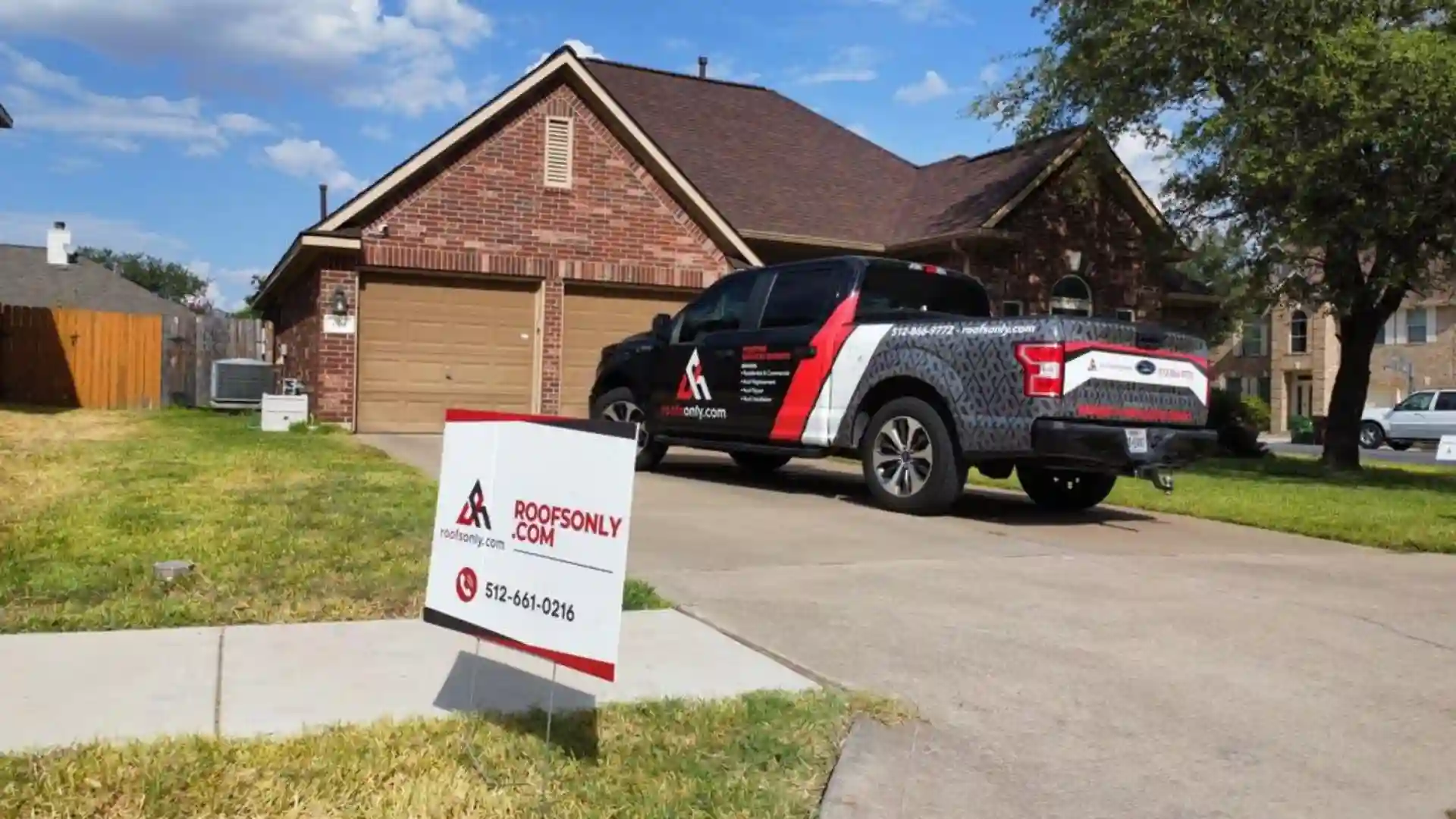 a brick house with a brown roof, a driveway, and a parked truck