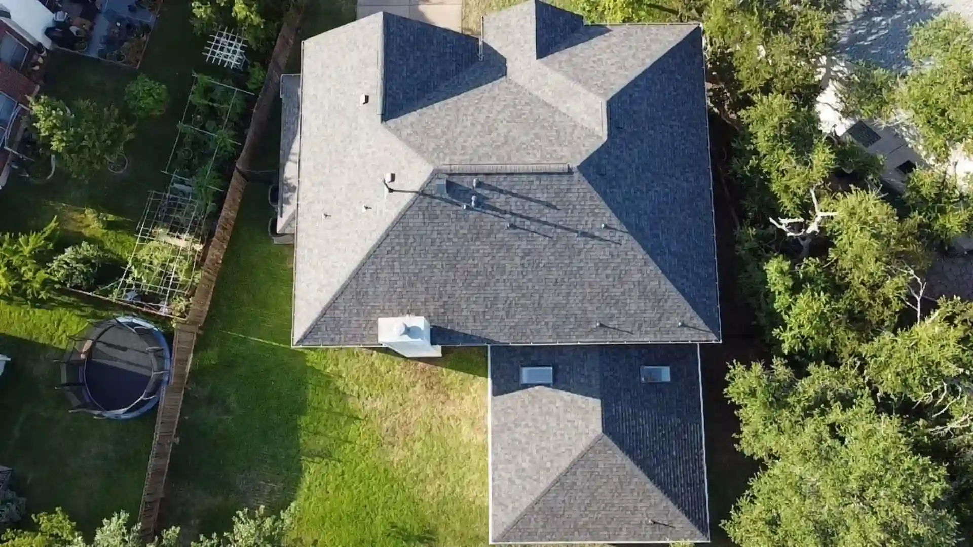 Aerial view of a dark gray shingle roof featuring multiple ridges and rooftop vents.