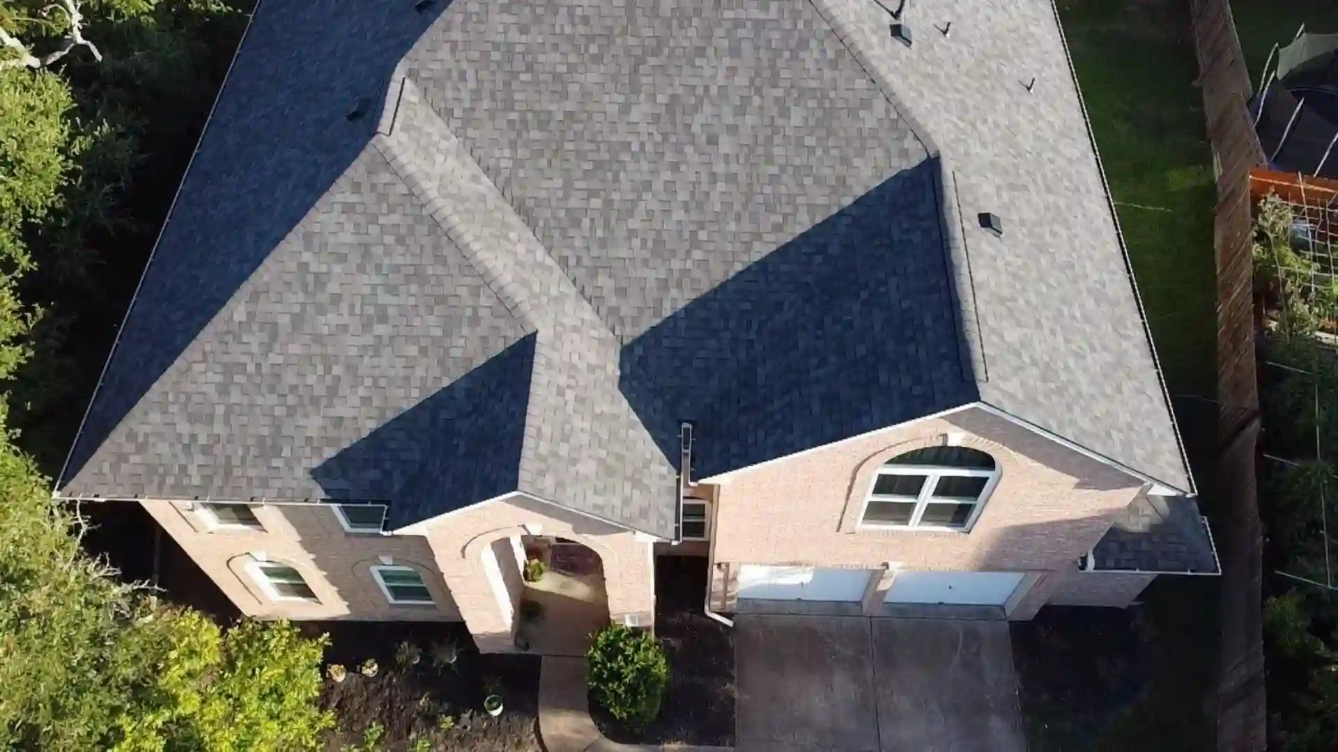 Aerial view of a gray shingle roof on a two-story house with an attached garage