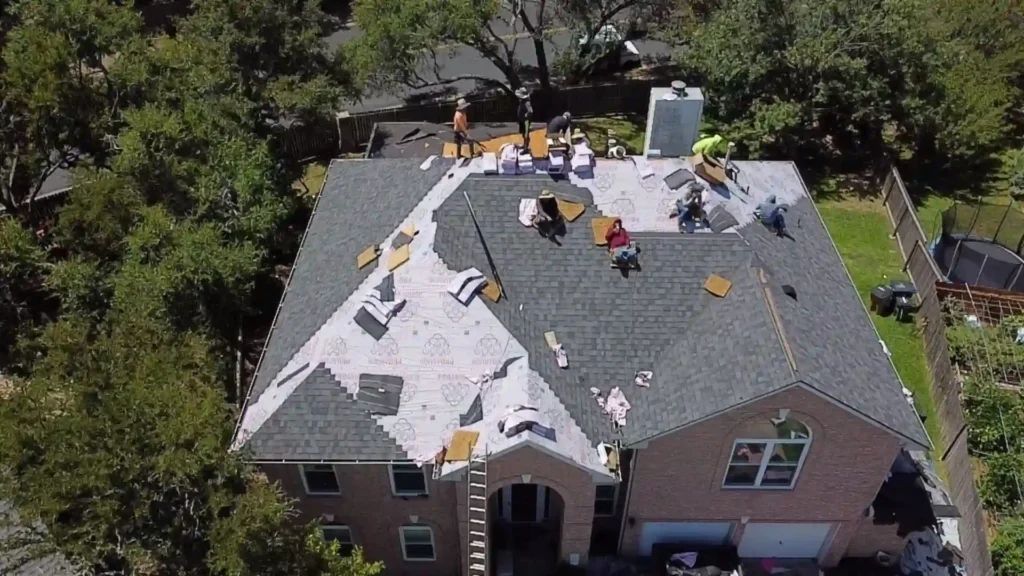 Crew installing new roof shingles on a two-story house