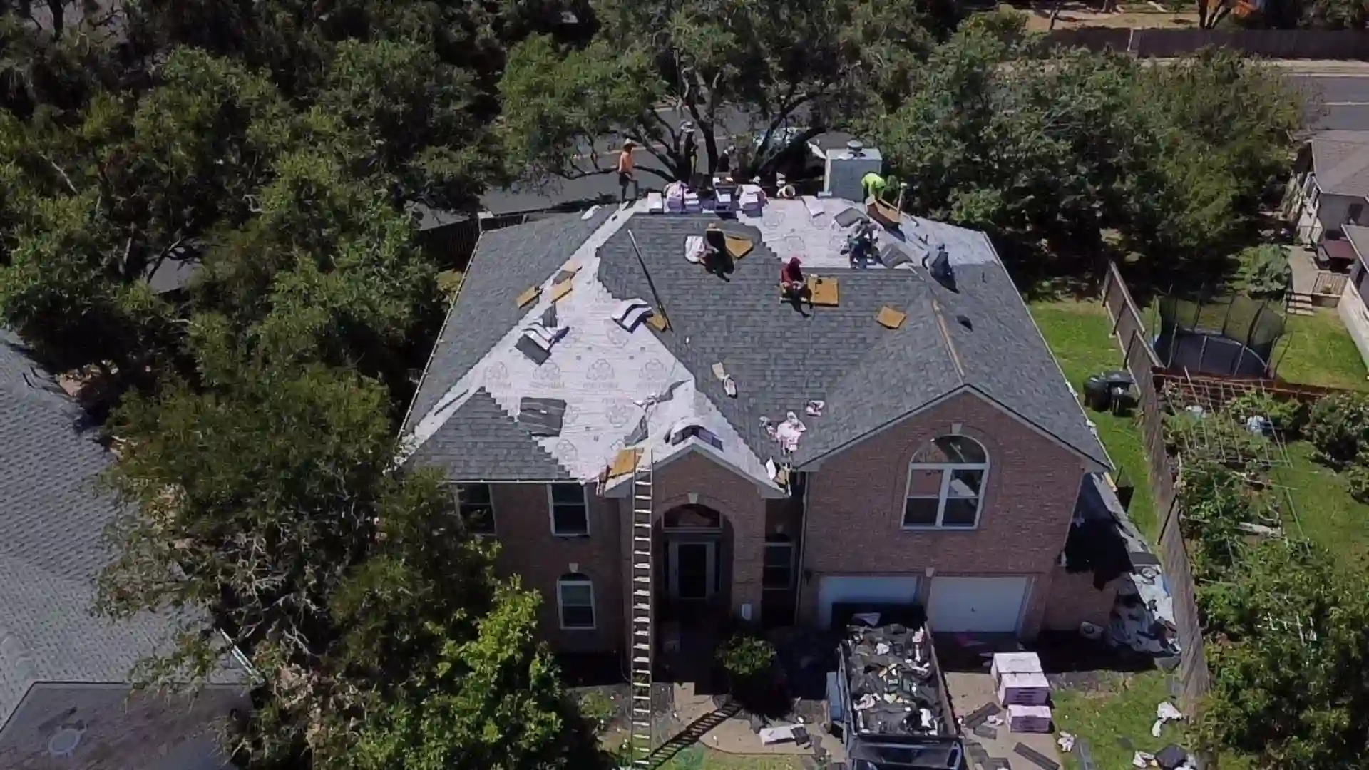 Crew replacing the roof on a two-story brick house.