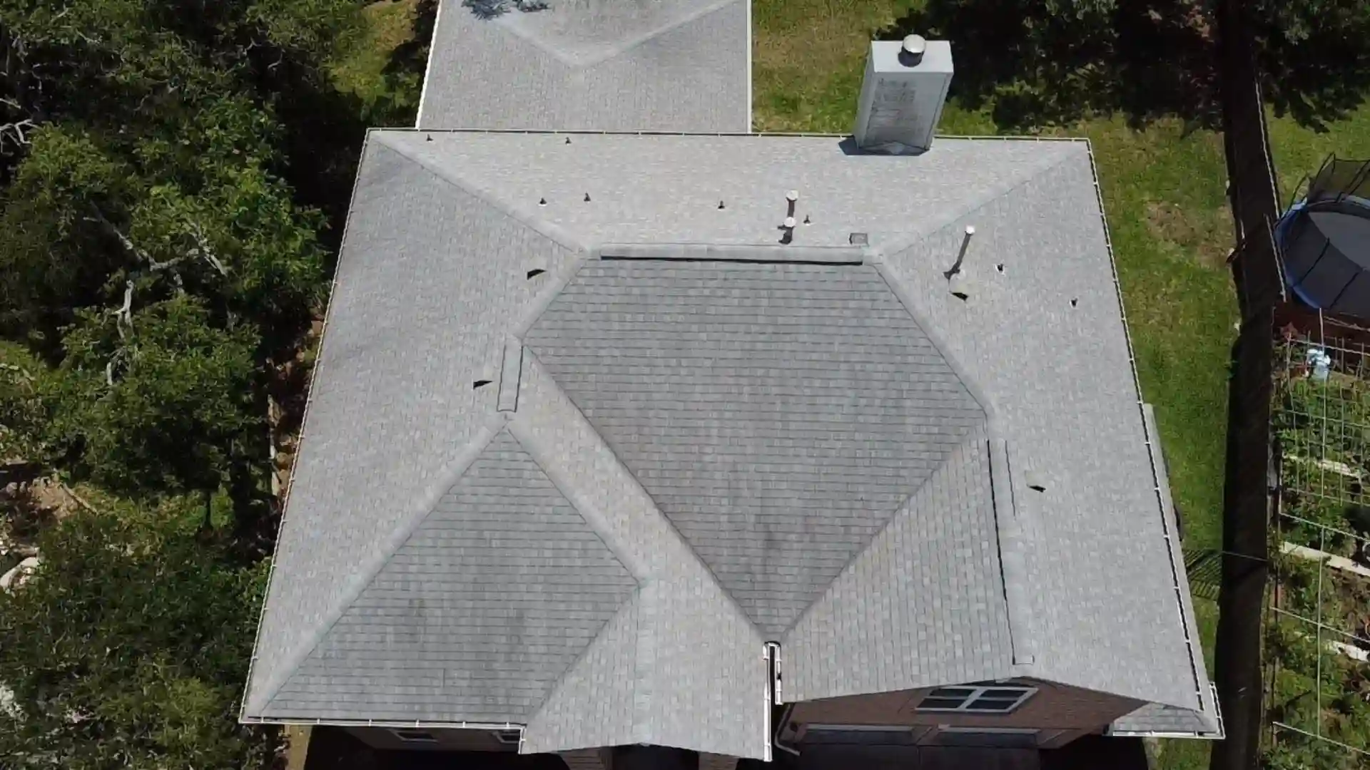 Aerial view of a light-gray shingle roof with multiple ridges and vents