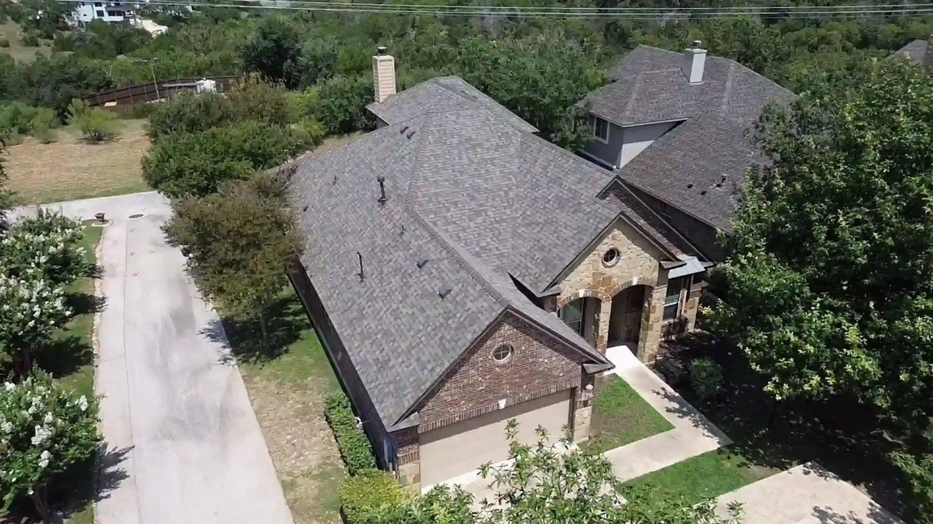 Aerial view of a suburban house with an asphalt shingle roof.