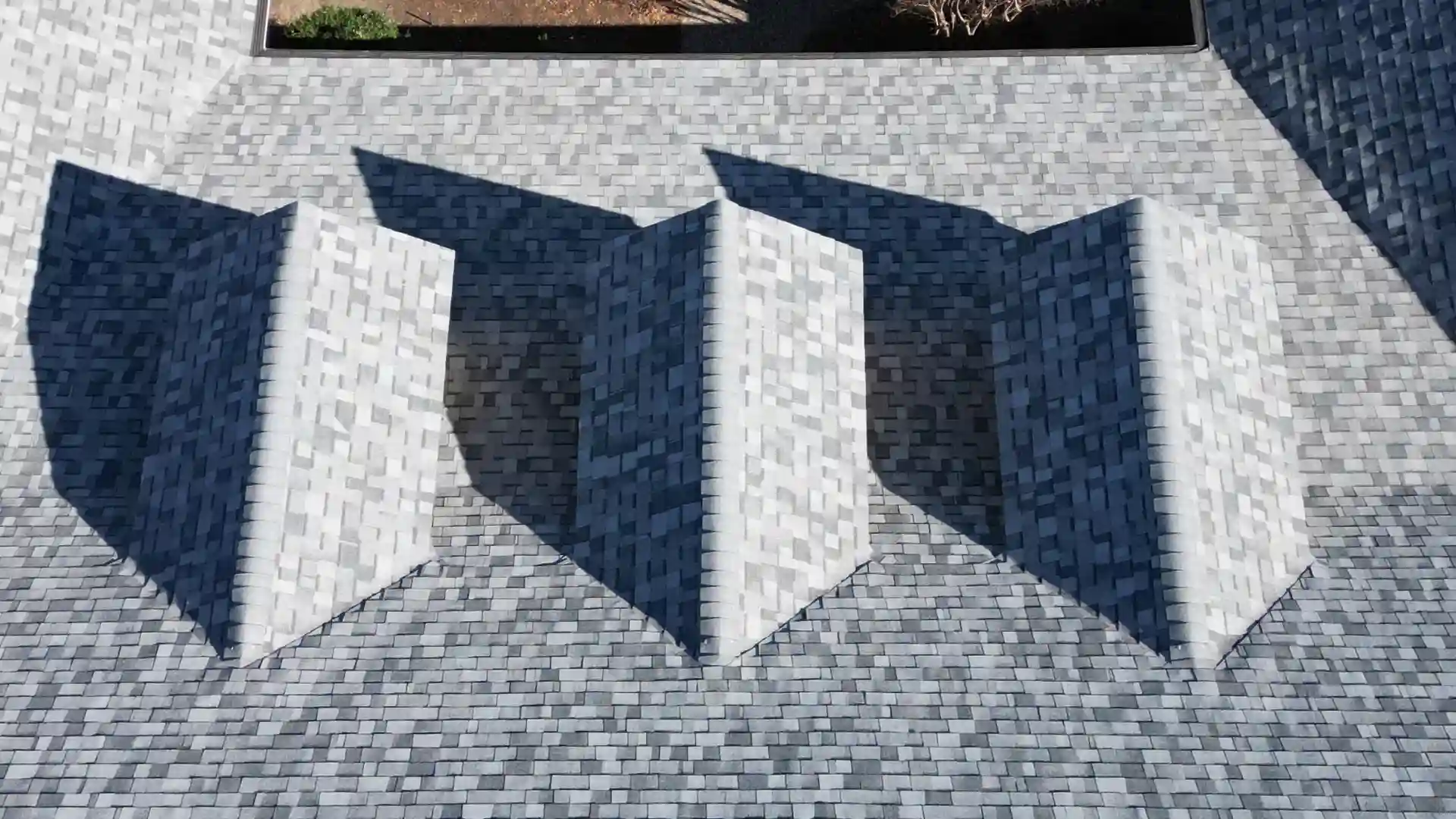 Close-up aerial view of a patterned tile roof with prominent shadows.