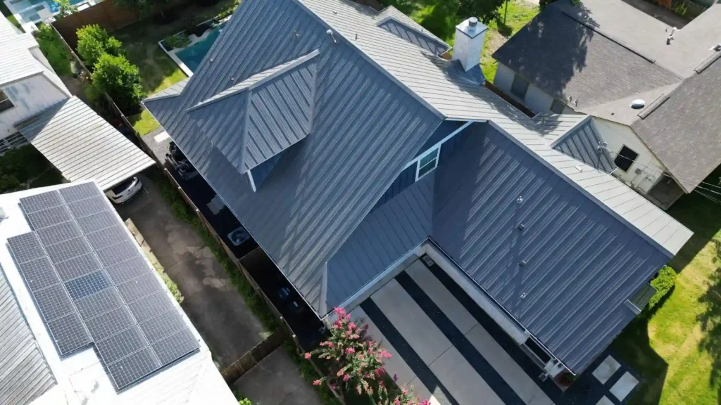 Aerial view of a house with a dark gray standing seam metal roof.