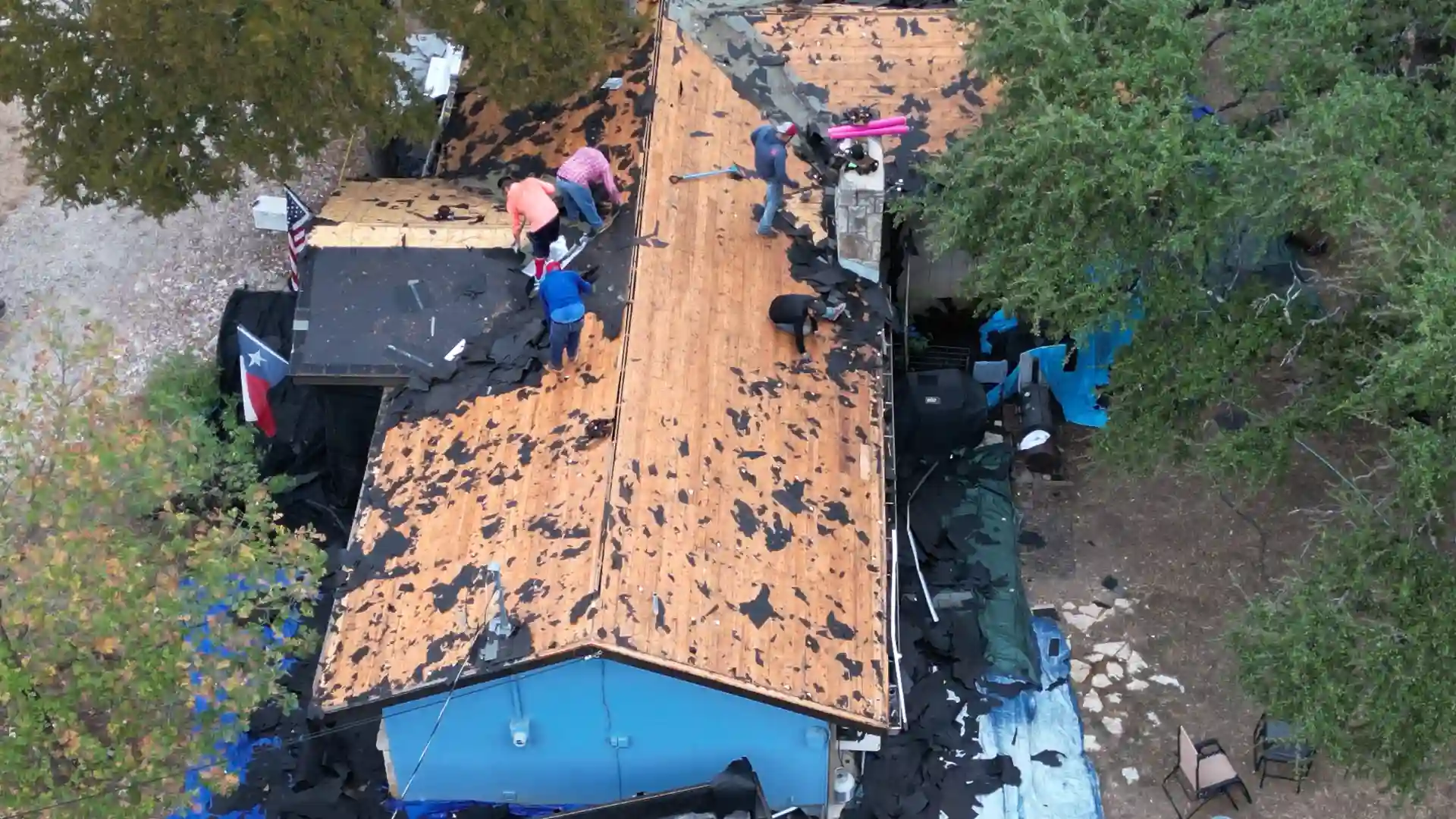 Roofing crew removing old shingles from house roof