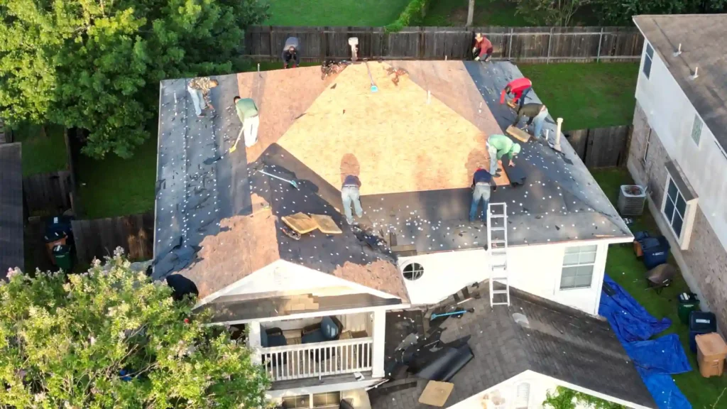 Roofing crew removing old shingles and preparing roof deck.
