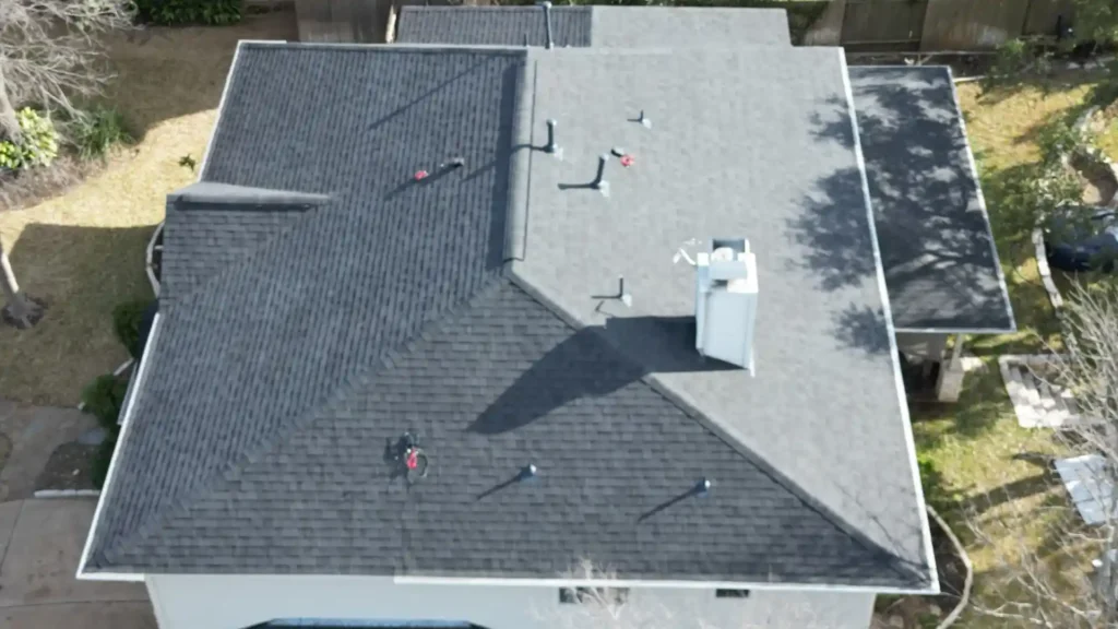 Aerial view of house with mixed shingle and flat roof.