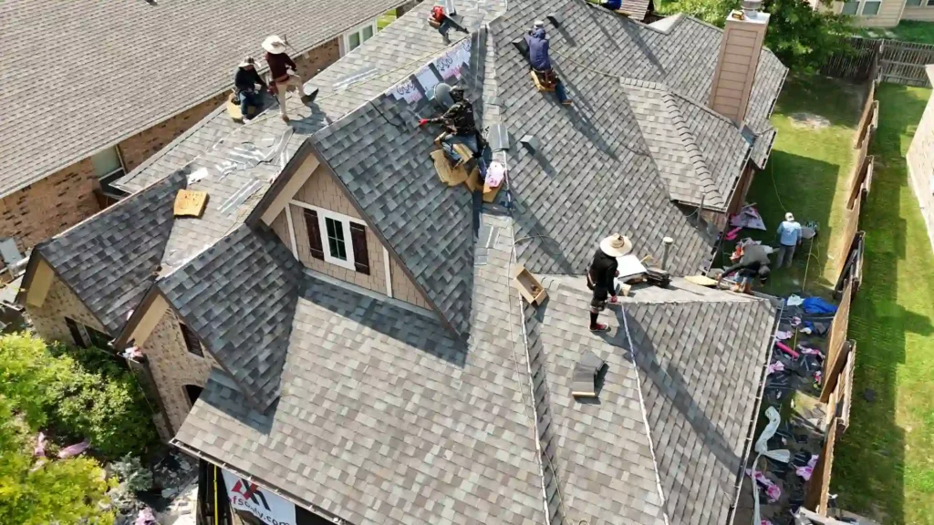 Roofing crew installing new shingles on house