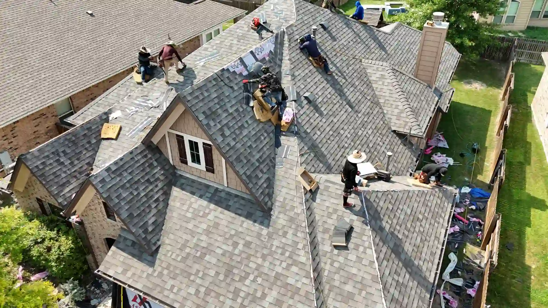 Roofing crew installing new shingles on house