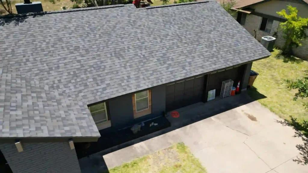 Aerial view of a residential roof in Austin, Texas, showcasing asphalt shingles and adjacent garage, emphasizing the importance of roof inspections for weather resilience.