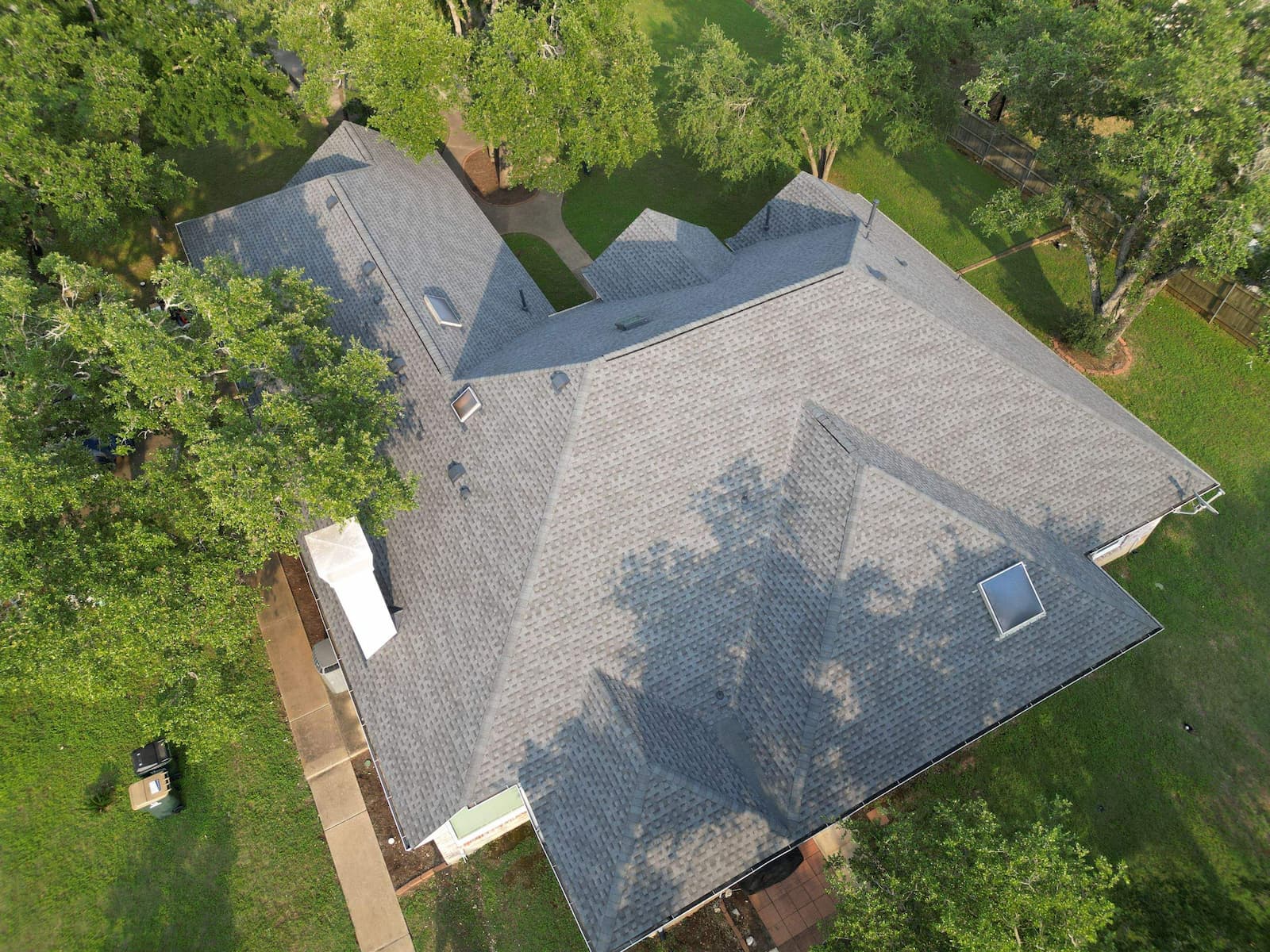 Completed roof replacement on a mature Shady Hollow home with surrounding tree canopy