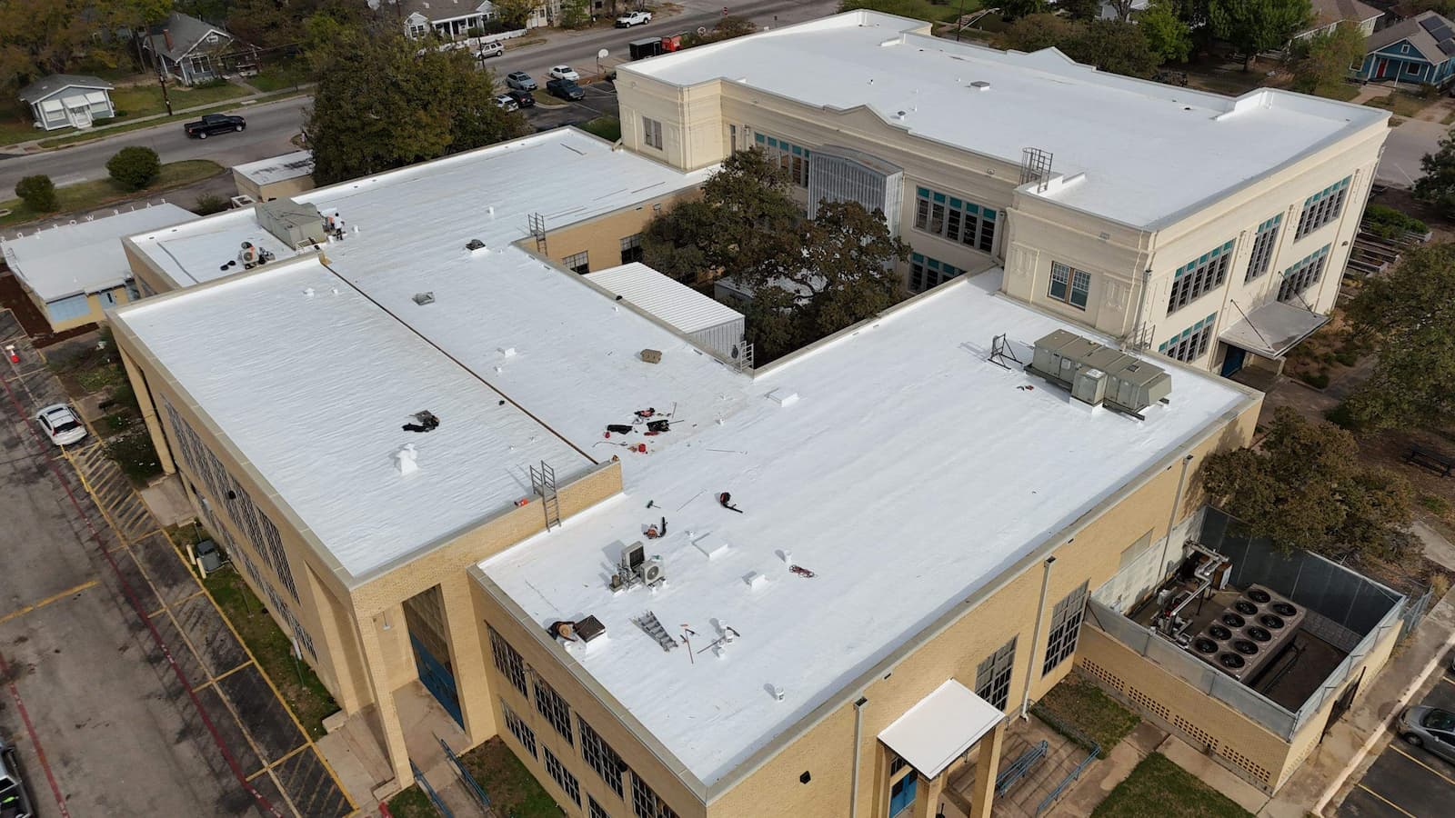 Aerial view of a large commercial TPO flat roof in Austin, TX, featuring a newly applied white silicone roof coating for energy efficiency.