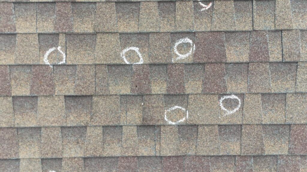 Chalk-marked hail damage on asphalt shingles during roof inspection in Easton Park TX