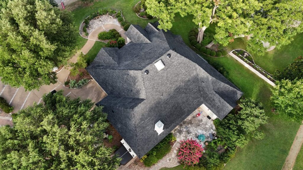 Aerial view of completed class 4 impact resistant architectural shingle roof replacement on established Georgetown TX home surrounded by mature tree canopy by RoofsOnly.com