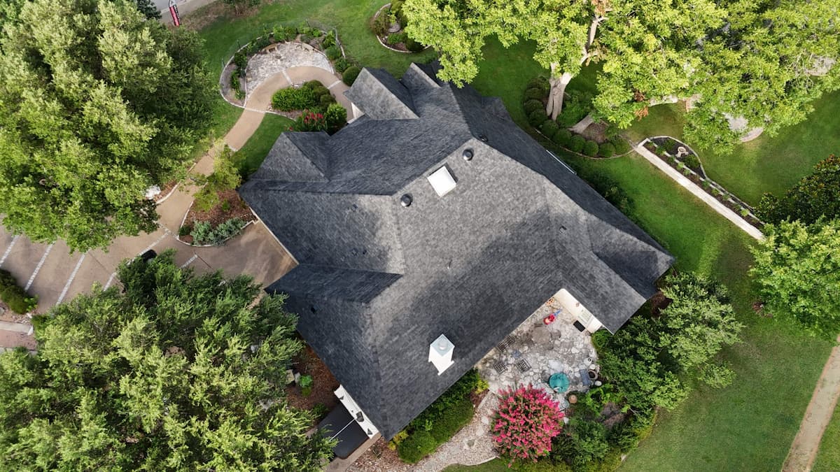 Aerial view of completed architectural shingle roof replacement on established Georgetown TX home surrounded by mature tree canopy by RoofsOnly.com