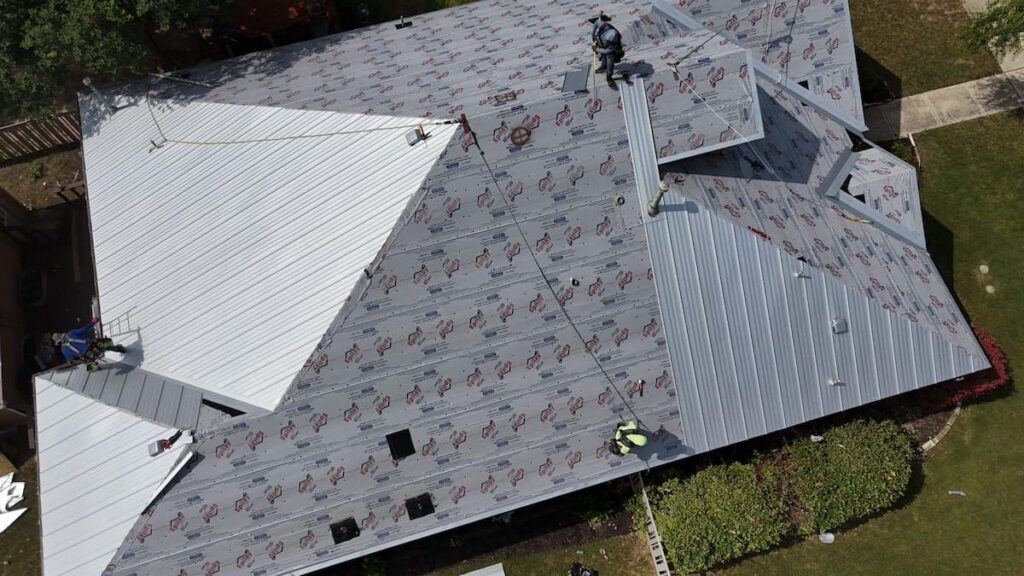 RoofsOnly.com crew installing standing seam metal roofing panels on a residential home in Austin Texas