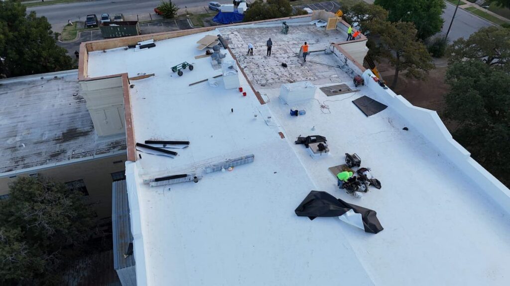 RoofsOnly.com contractor inspecting and repairing a flat roof leak on a commercial building in Austin Texas