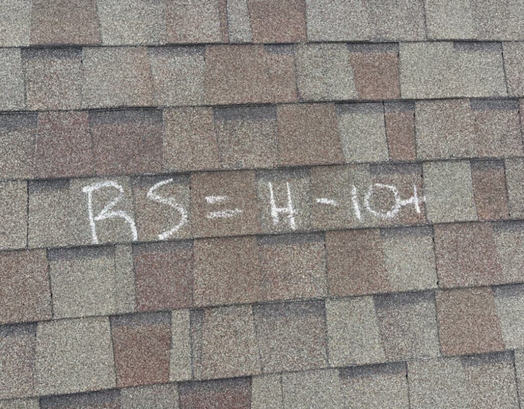 Roof slope chalk-marked with hail hit count during a Round Rock hail damage inspection