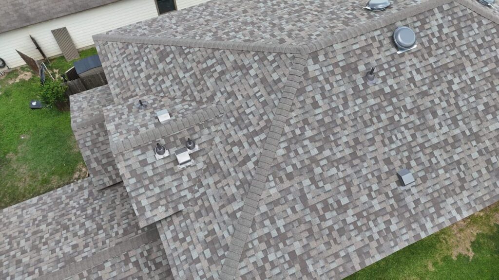 Aerial drone photo showing a completed Owens Corning architectural shingle roof replacement featuring roof vents and pipe jack flashing on a house in Austin, TX.