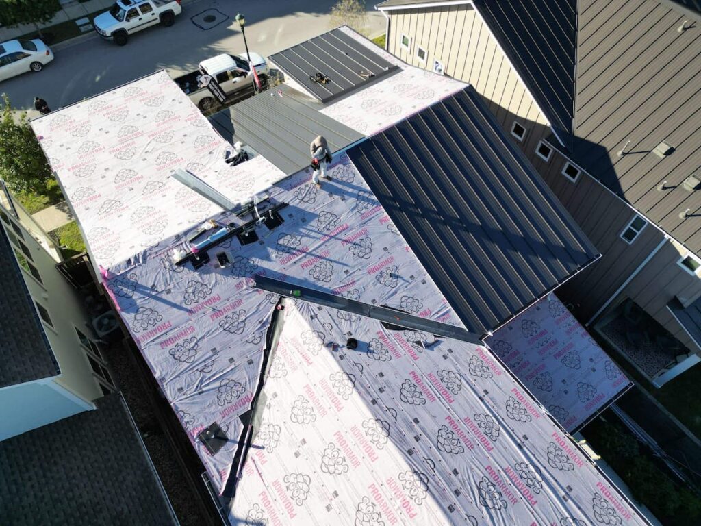 Underlayment installment being installed under a standing seam metal roof in Austin